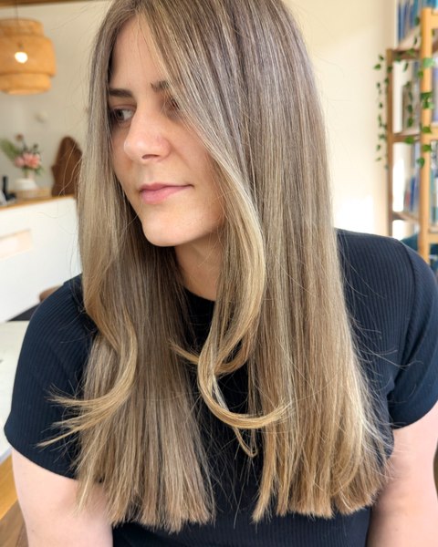 A lived-in balayage on long straight hair, soft at the root and lighter through the ends
